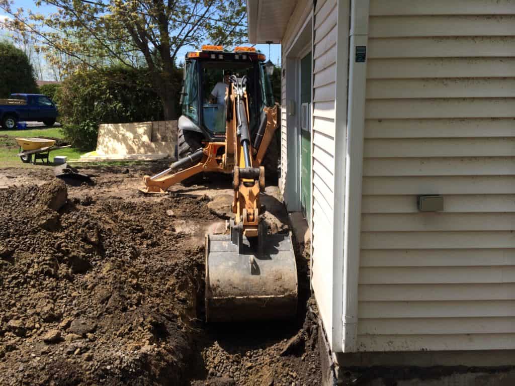 Digger excavating to waterproof the foundation